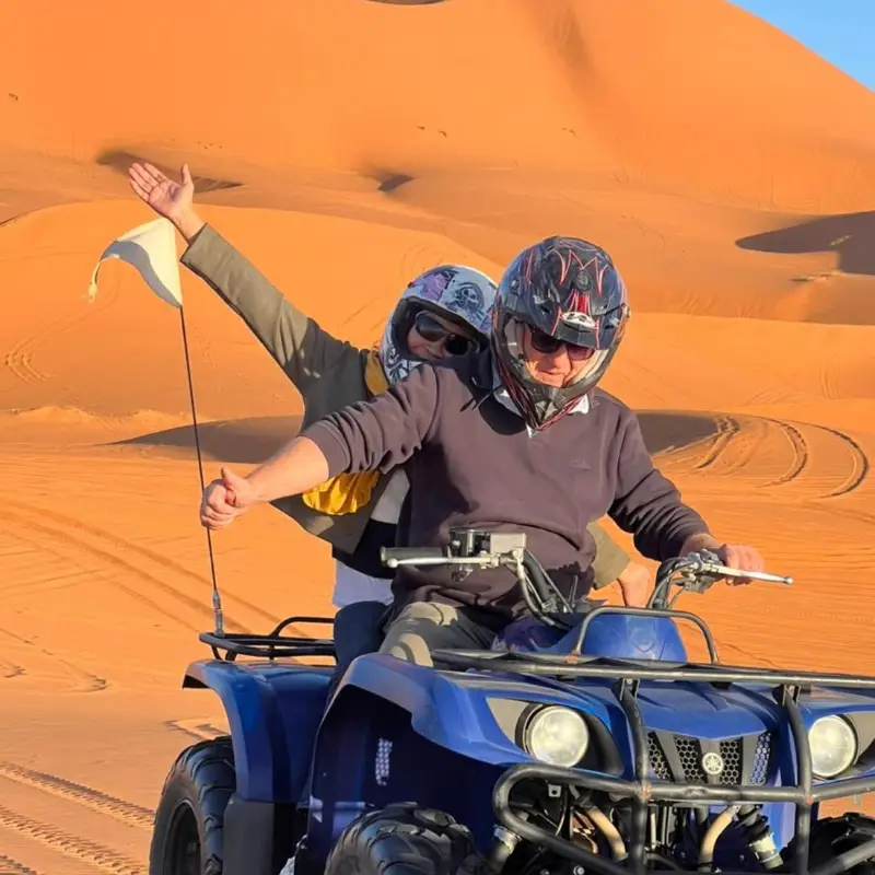Rider waving a flag on a blue quad in the Merzouga dunes