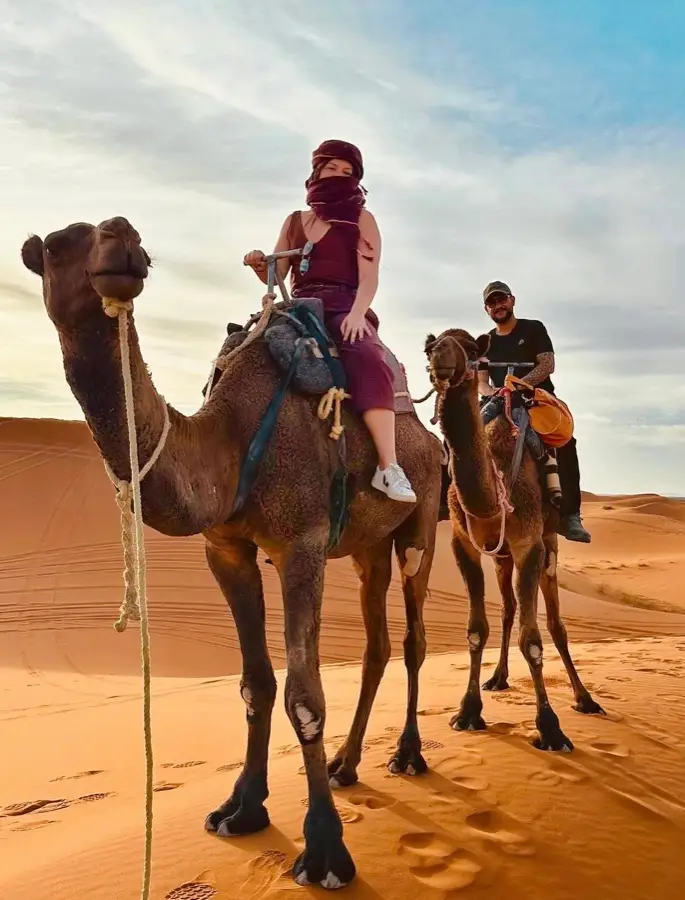 Two travellers riding camels in the Merzouga dunes