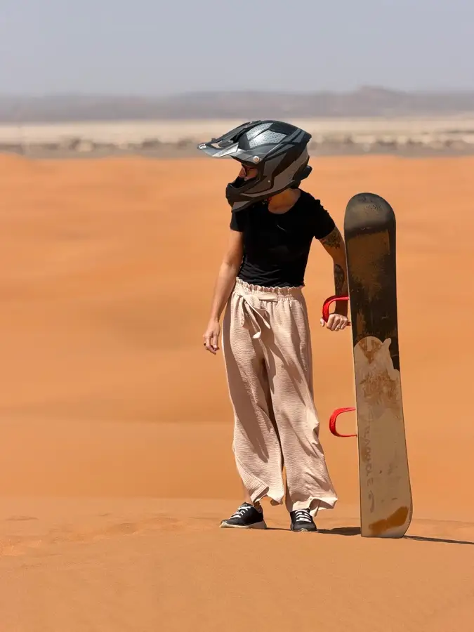 Rider standing with a sandboard in the dunes