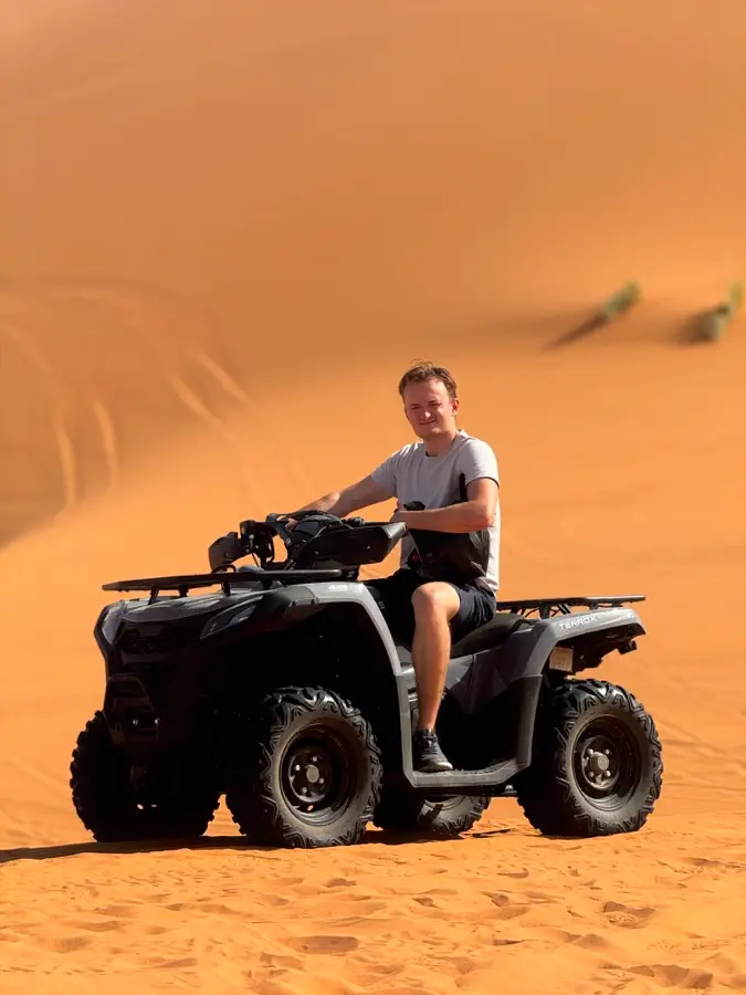 Rider on a black quad bike in the Sahara dunes