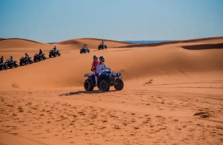 Line of quad bikes riding through the dunes of Merzouga