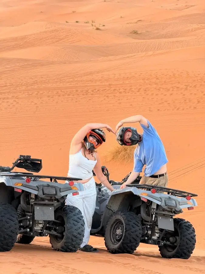 Couple making a heart sign beside their quad bike in Erg Chebbi