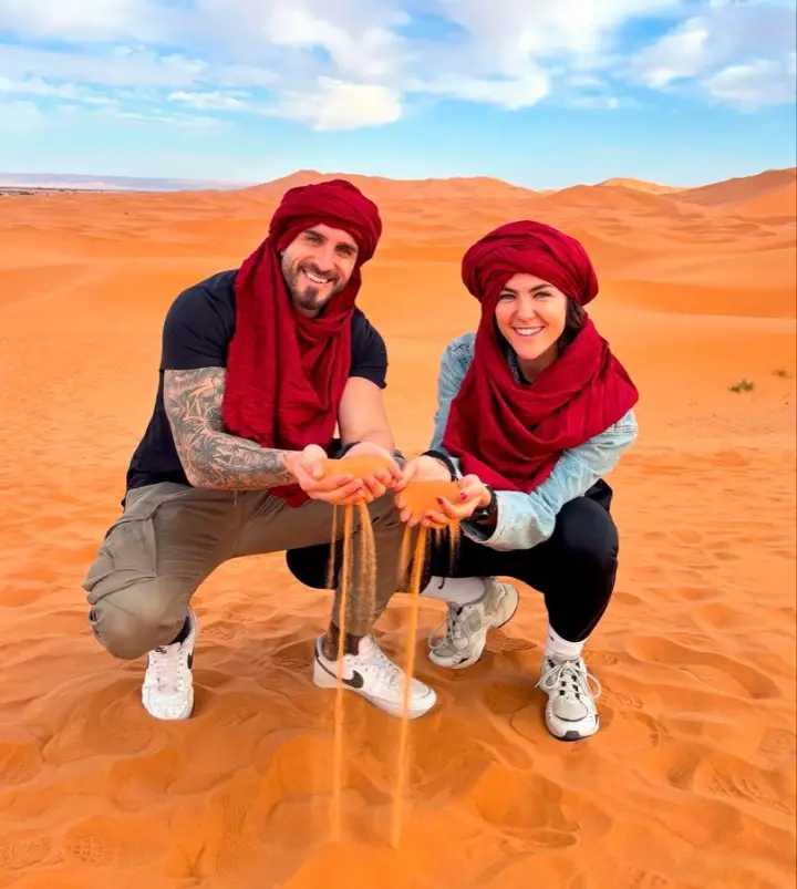 Couple in desert turbans playing with Sahara sand in Merzouga