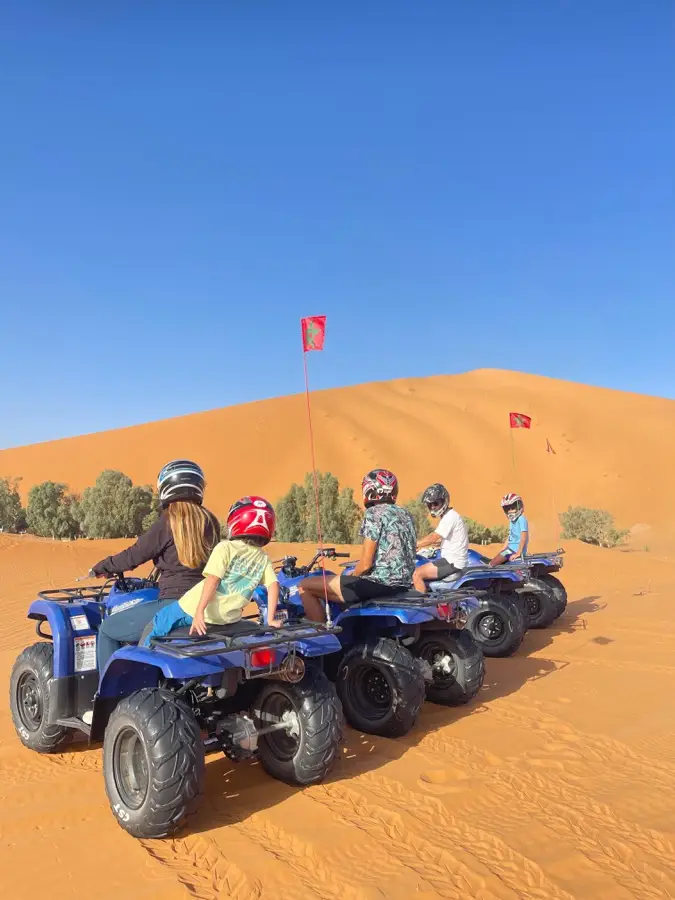 Group on quad bikes at the foot of a high Erg Chebbi dune
